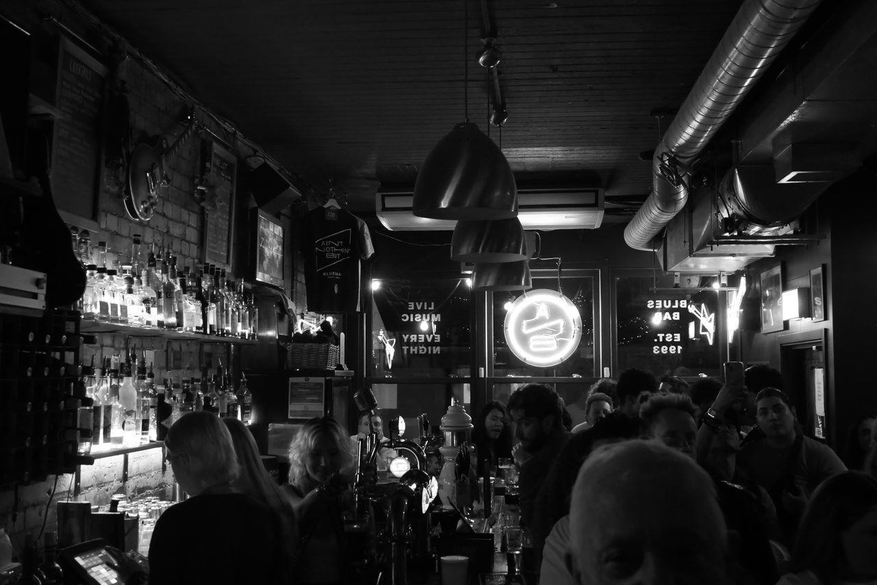 Last Orders. A packed bar, lit from behind the counter.